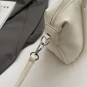 Detailed close-up of silver lobster clasp and metal zipper on lychee leather handbag