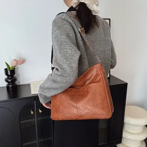 Detail der braunen Leder-Hobo-Tasche mit ethnisch gemustertem Jacquard-Schultergurt