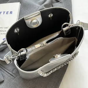 Top view of silver bucket bag with magnetic closure, chain handle and black inner lining