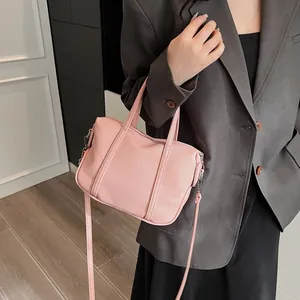 Close-up of pink lychee textured handbag styled with a grey blazer for a modern fashion look