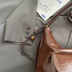 Detail of vintage brown glossy leather shoulder bag with white stitching and woven strap