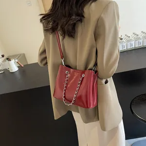 Detail of burgundy glossy patent leather bag with silver chain and shoulder strap
