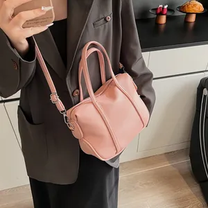 Close-up of pink litchi grain texture and silver hardware on a crossbody handbag