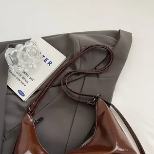 Detailed view of dark brown glossy leather shoulder bag with contrast stitching and zipper