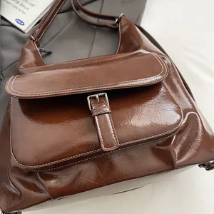 Detail view of vintage brown oiled leather bag with white contrast stitching and buckle