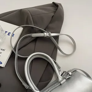 Detail of silver metallic baguette bag with dual handles and adjustable shoulder strap