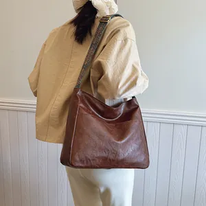 Detail eines breiten bestickten Schultergurts mit Vintage-Muster auf brauner Tasche