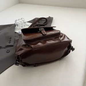 Detail of vintage dark brown leather backpack with buckle pocket and glossy texture