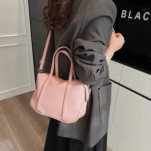 Pink lychee texture Boston bag worn with a gray suit for a stylish commuter look