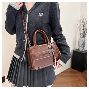 Detail of vintage brown glossy tote bag with charms and embossed logo texture