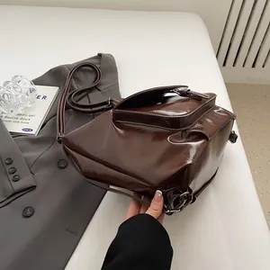 Detail of dark brown glossy leather shoulder bag with large capacity and metal buckles