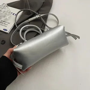 Detail of silver metallic baguette bag with top handles and adjustable shoulder strap