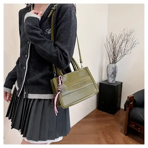 Army green glossy leather tote bag with tassel charm shown in a lifestyle setting