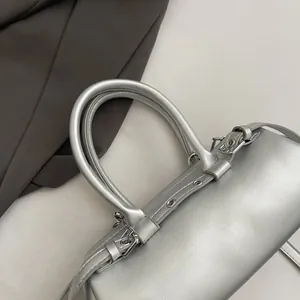 Detailed macro view of silver metallic cylindrical handbag with top handles and strap