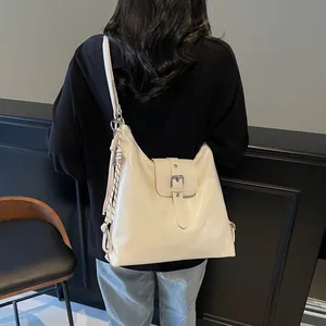 Detailed back view of model wearing a glossy cream white large shoulder bag with silver buckle