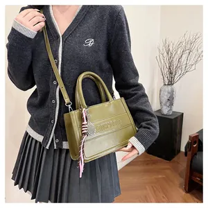 Detail of olive green structured tote bag with embossed letters and pink tassel