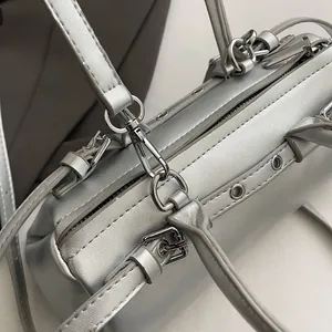 Detailed close-up of metallic silver barrel bag showing zipper and polished hardware