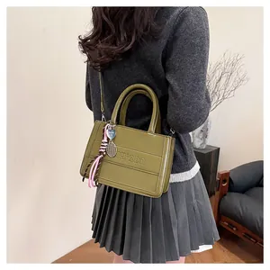 Detail of dark green glossy tote bag with IH'2DN logo and tennis racket charms