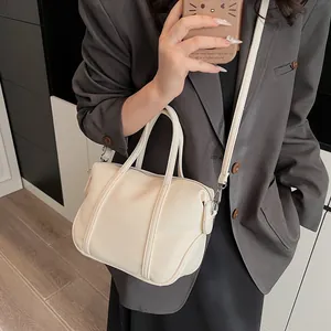 Litchi pattern crossbody bag in off-white carried by model in casual daily scene