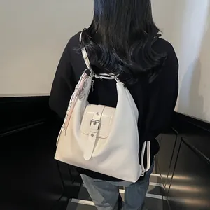 On-body view of a white vintage backpack with buckle detail and pink checkered scarf accessory