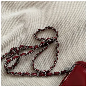 Close-up of a red leather crossbody bag with silver metal chain and zipper detailing