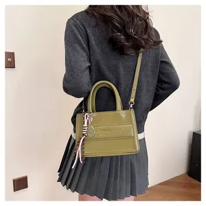 Detail of olive green PU leather tote bag featuring embossed letters and tennis racket charm