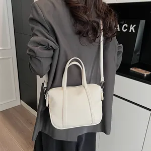 Close-up of cream lychee grain leather handbag with dual handles and detachable strap