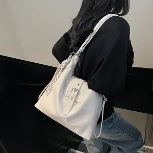 Detail of white large capacity tote bag with silver buckle and black-white scarf pendant