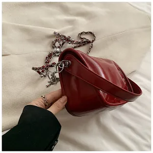 Detail of burgundy glossy leather bag with silver metal chain strap and polished finish