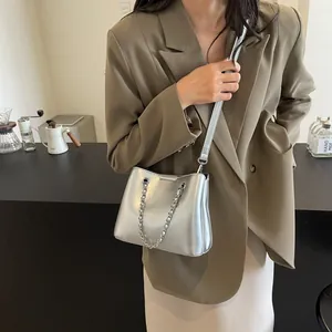 Detail of silver metallic bucket bag with stylish chain element and fine shoulder strap
