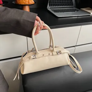 Detail of cream barrel bag with silver buckles, metal eyelets and adjustable strap