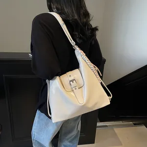 Detail view of cream white glossy leather tote bag with stylish braided strap ornament