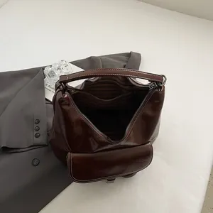 Detail of dark brown leather bag showing white contrast stitching and striped lining