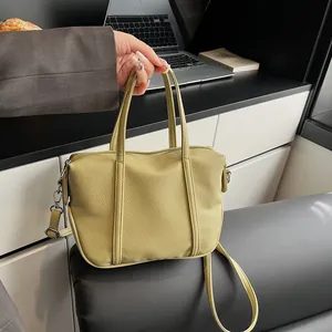 Detail of light green litchi texture leather handbag showing handles and metal buckles