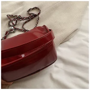 Close-up of red patent leather crossbody bag with silver chain and textured ball detail