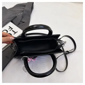 Interior view of black glossy tote bag with zipper closure and pink knot charm