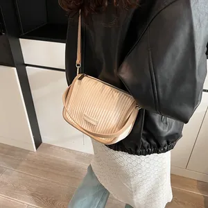 Detail der beige plissierten Umhängetasche mit Goldbeschlägen und Modemarke-Tag