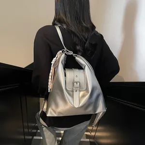Close-up of metallic silver backpack with adjustable buckles and striped scarf detail