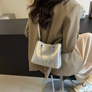 Detail of silver metallic shoulder bag with leather strap and decorative silver chain