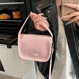 Detail der rosa Umhängetasche mit vertikaler Plissee-Struktur und goldener Hardware