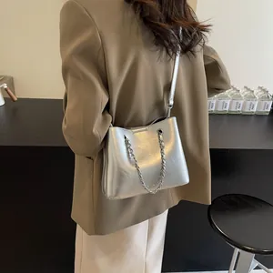 Close-up of stylish metallic silver bucket bag with chain strap detail on model