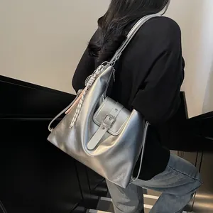 Silver metallic crossbody bag with silk scarf charm shown on model in modern setting