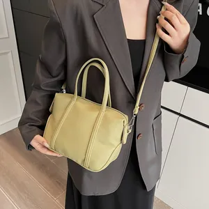 Detail of light green lychee pattern leather handbag shown with crossbody strap on model