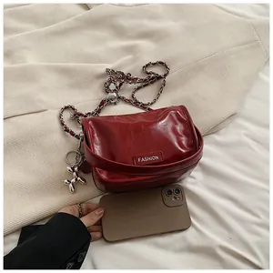 Detail of red glossy chain bag with silver balloon dog charm and FASHION label