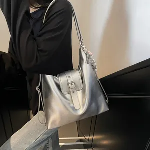 Chic silver metallic tote bag shown on shoulder in a minimalist urban setting