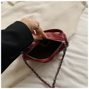 Detail view of red patent leather crossbody bag with silver chain strap and inner pocket
