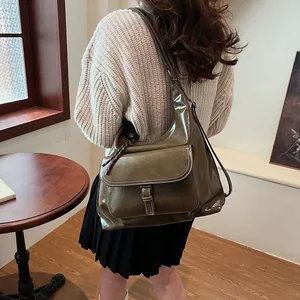 Detailed view of an olive green glossy hobo bag with contrast stitching and pocket