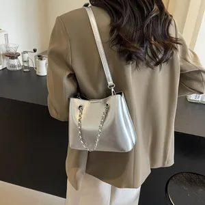 Detail of silver metallic shoulder bag with leather strap and decorative chain