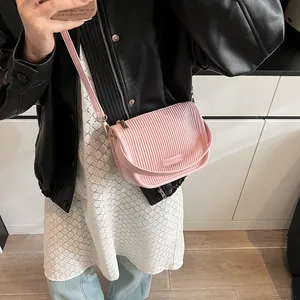 Detailansicht der rosa plissierten Umhängetasche mit Metallschnalle und Logo-Schild
