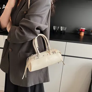 Detail of a beige baguette bag with tassel and strap shown in a modern lifestyle setting
